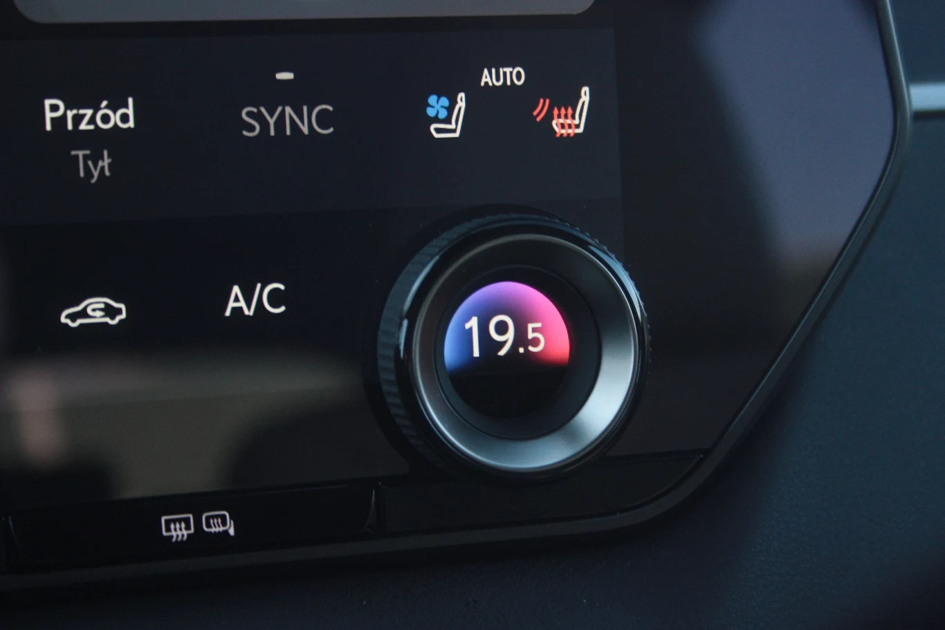 panel sterowania klimatyzacją samochodową z wyświetlaną temperaturą 19,5°C, przyciskiem A/C, ikoną obiegu powietrza oraz ustawieniami ogrzewania i chłodzenia siedzeń