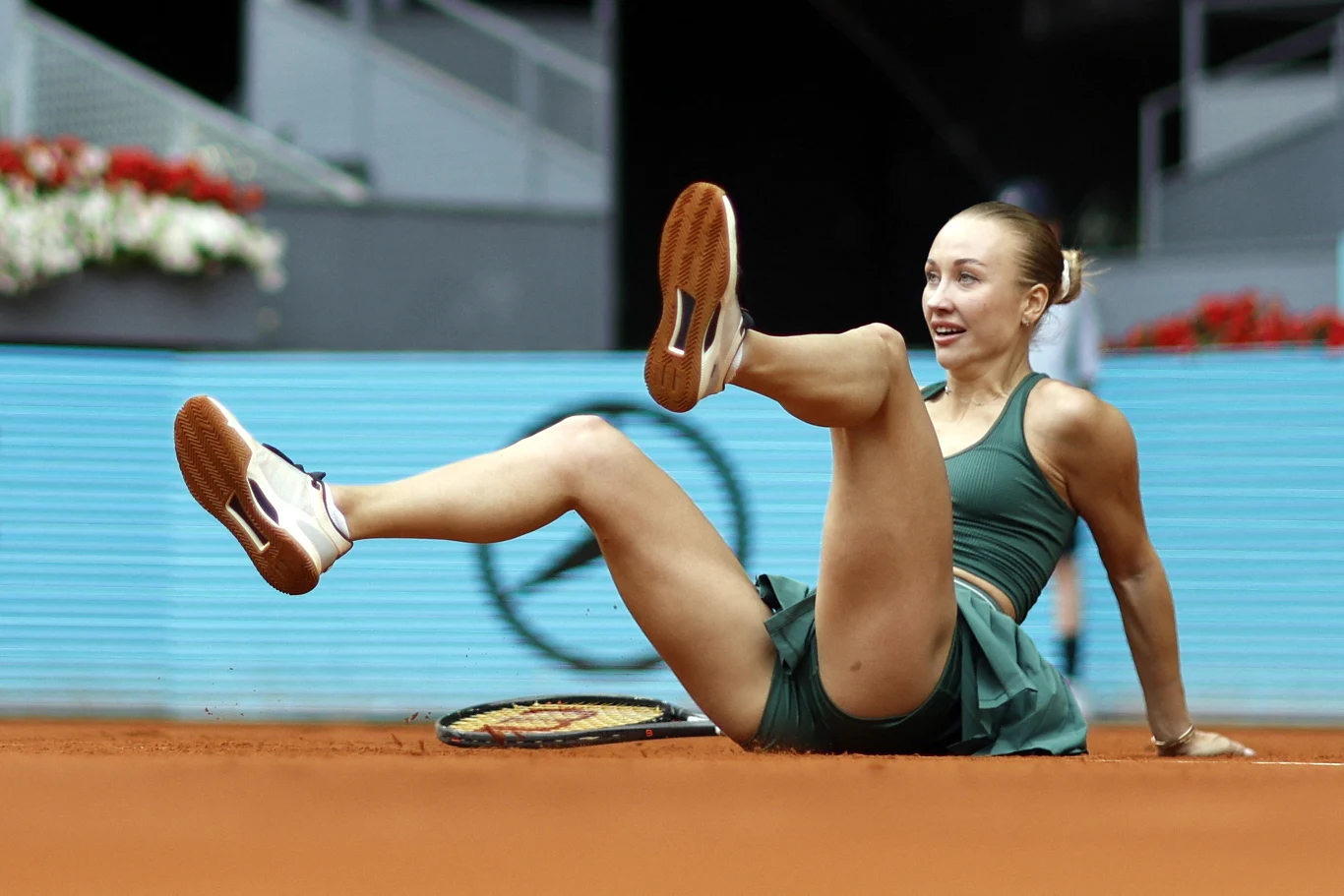 Anastazja Potapowa, Madryt 2026 tenisistka siedzi na kortcie ziemnym po upadku podczas meczu, z rakietą leżącą obok i uśmiechem na twarzy