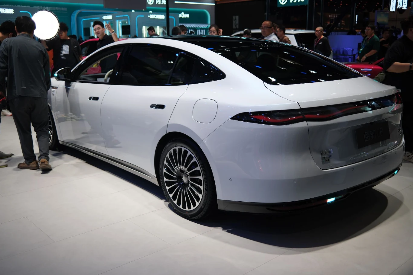 BYD Seal 08 i Sealion 08 mają pozwalać na ładowanie akumulatora niemal do pełna w 9 minut. biały, nowoczesny samochód elektryczny o aerodynamicznym kształcie nadwozia, przyciemnianych szybach i wyrazistych, poziomych tylnych światłach LED, stojący na dużych, designerskich felgach podczas targów motoryzacyjnych, otoczony przez zainteresowanyc...