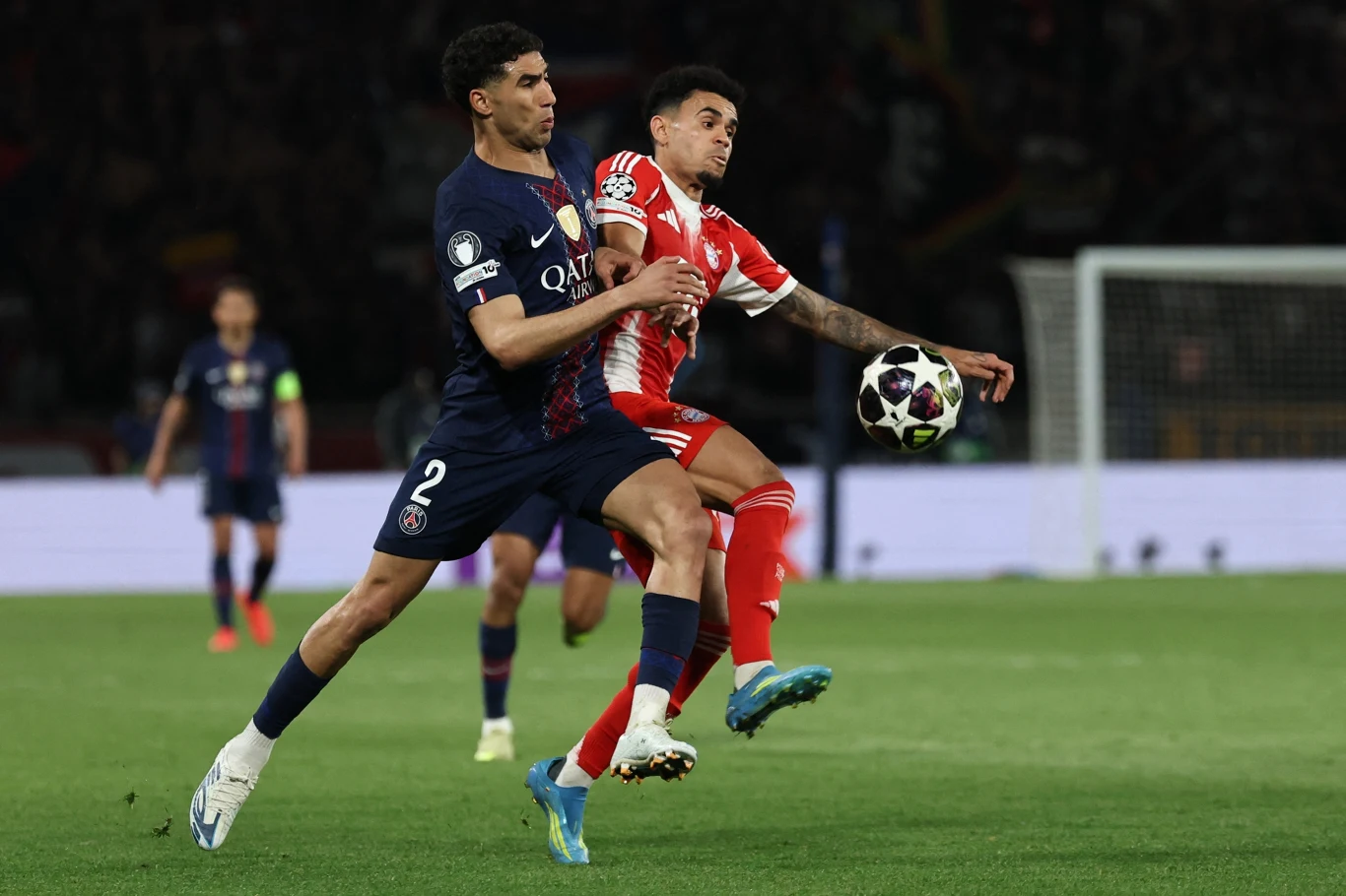 dwóch piłkarzy walczy o piłkę podczas meczu, jeden z nich ubrany w ciemny strój PSG, drugi w czerwono-białe barwy drużyny przeciwnej, na pierwszym planie dynamiczna rywalizacja o posiadanie piłki