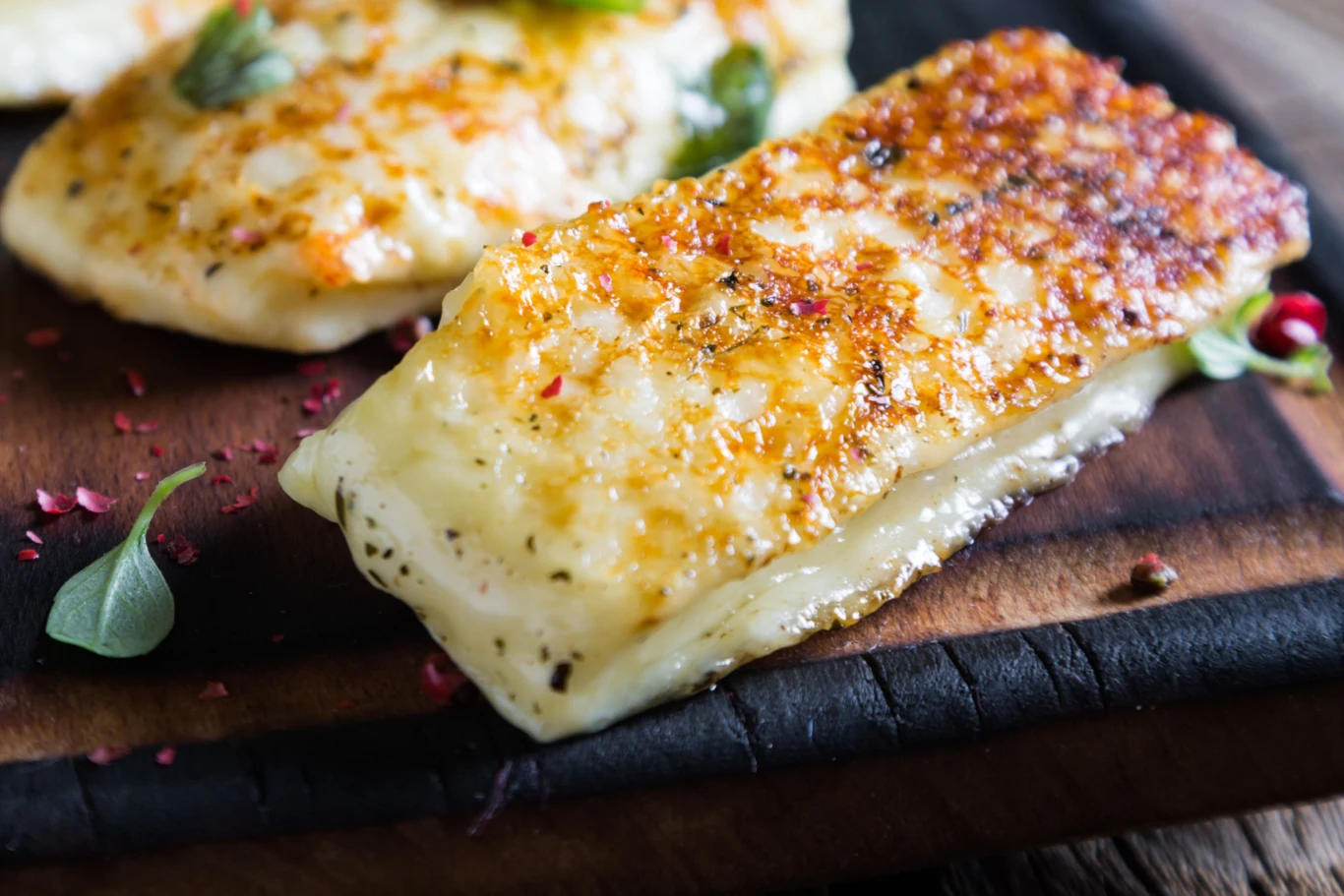Grillowany ser halloumi w miodowej glazurze to idealna przekąska na weekend Grillowany ser halloumi w miodowej glazurze na drewnianej desce, z ziołami i czerwonym pieprzem