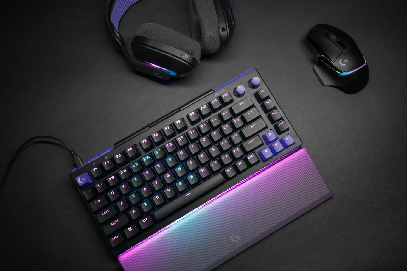 Klawiatura mechaniczna z podświetleniem RGB, bezprzewodowa mysz komputerowa oraz słuchawki gamingowe na czarnym tle, wszystkie urządzenia utrzymane w nowoczesnym stylu z kolorowym oświetleniem LED.