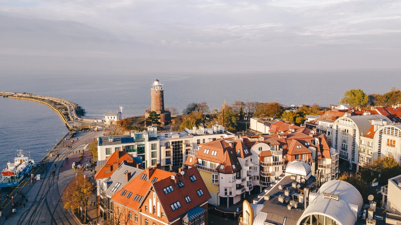 Kołobrzeg jest miastem stworzonym do aktywności, która nie niszczy ciała panorama nadmorskiego miasta z charakterystyczną latarnią morską, czerwonymi dachami kamienic oraz widokiem na morze i falochron ciągnący się w głąb wody