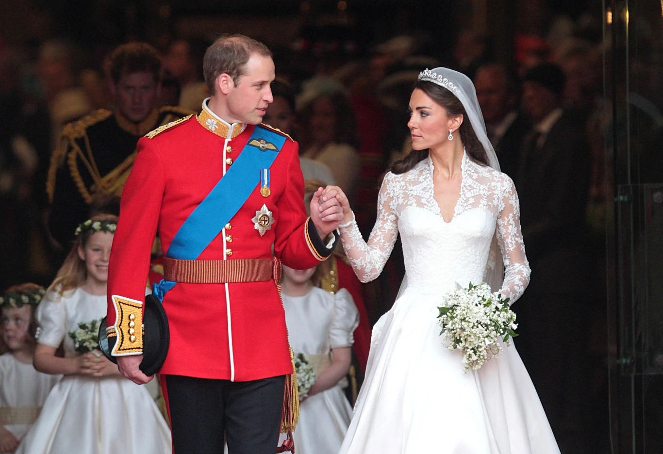 Książę i księżna Walii podczas ślubu w 2011 roku Książę William i księżna Kate podczas ślubu w 2011 roku, idą razem w strojach ślubnych; obok druhny.