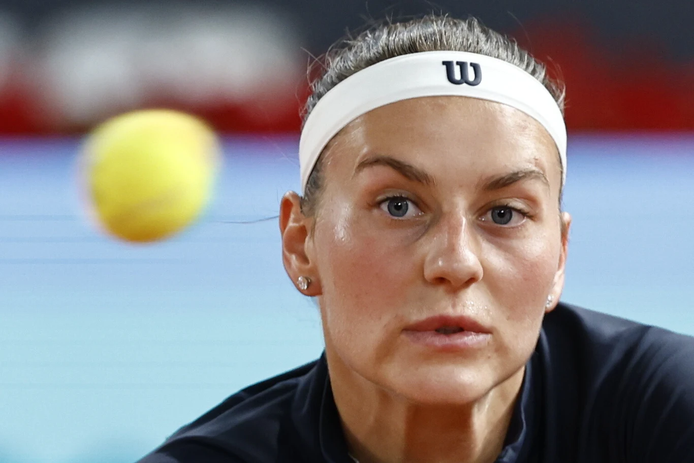Marta Kostiuk, Madryt 2026 tenisistka skupiona na piłce tenisowej lecącej tuż przed jej twarzą, ubrana w ciemną odzież sportową i białą opaskę z logo Wilson
