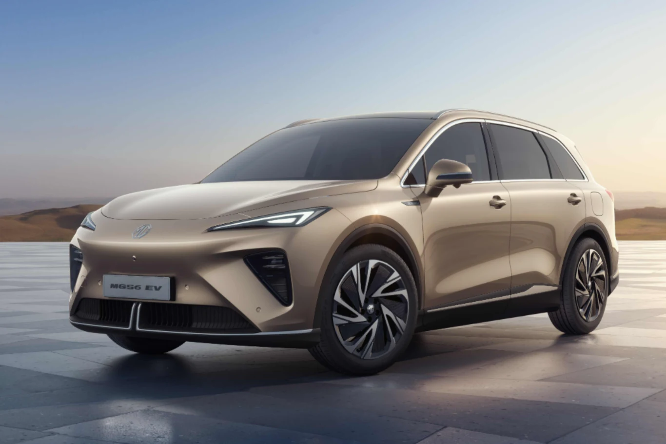 MG S6 dostępny będzie w wersji z napędem na tylną oś lub wszystkie koła. Nowoczesny, beżowy SUV elektryczny z aerodynamiczną sylwetką, ostro zarysowanymi reflektorami LED i przyciemnianymi szybami, ustawiony na eleganckich alufelgach na tle jasnego, otwartego krajobrazu.