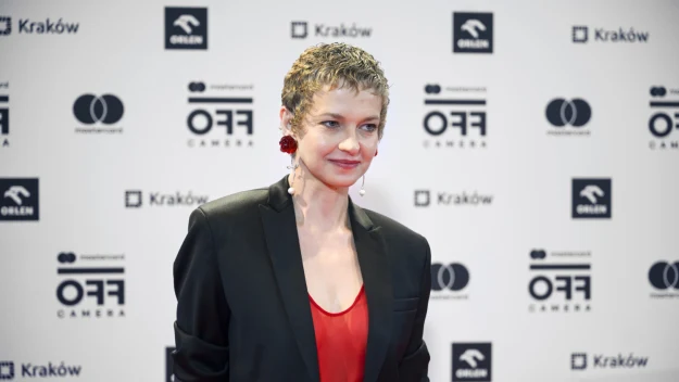 kobieta z krótkimi, blond włosami w czarnej marynarce i czerwonym topie pozuje na ściance podczas wydarzenia filmowego OFF CAMERA, tło z logotypami sponsorów i nazwą festiwalu