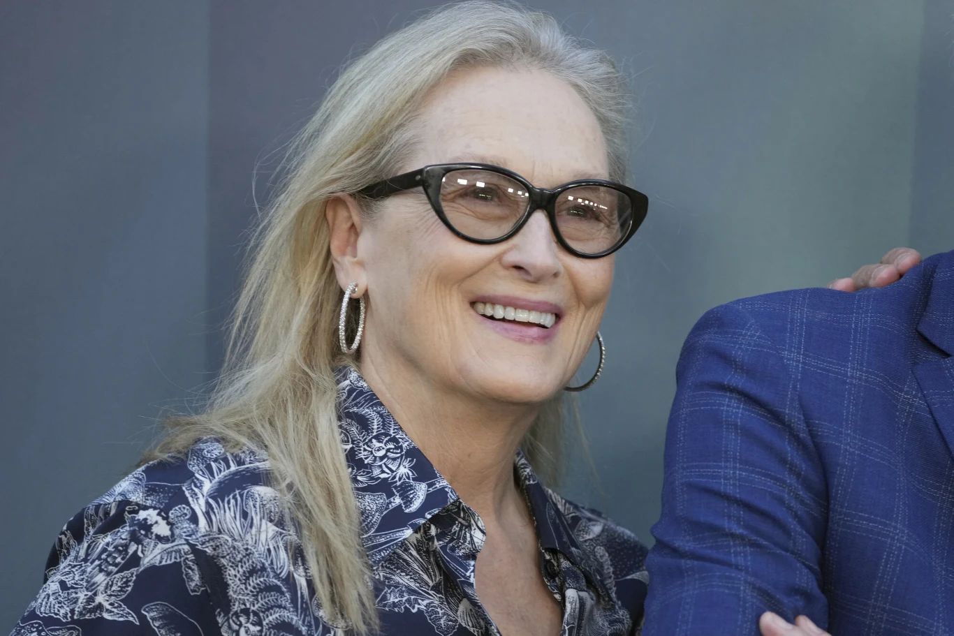 Meryl Streep Meryl Streep w okularach i koszuli w roślinny wzór stoi obok osoby w niebieskiej marynarce