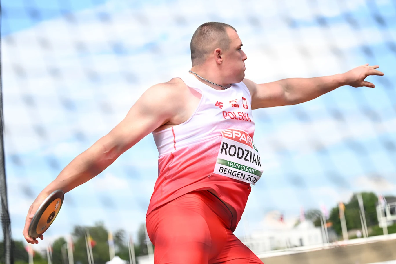 Damian Rodziak Lekkoatleta w stroju reprezentacji Polski wykonuje rzut dyskiem podczas zawodów, dynamicznie rozciągając ręce i koncentrując się na technice, z widoczną nazwą oraz numerem startowym na koszulce.