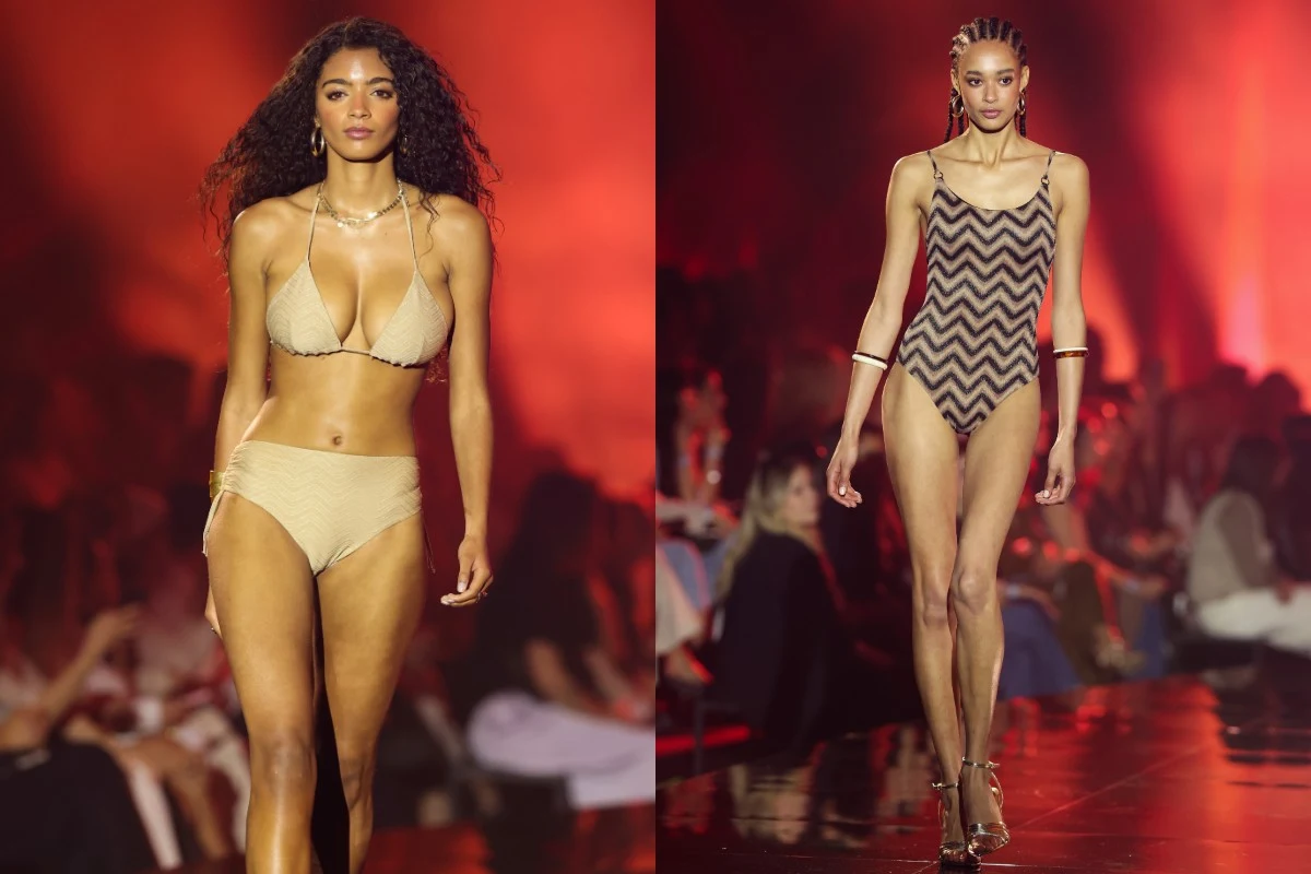 Najnowsze propozycje strojów kąpielowych od Tezenis Dwie modelki prezentujące stroje kąpielowe na wybiegu; po lewej modelka w jasnobeżowym bikini, po prawej modelka w jednoczęściowym kostiumie z geometrycznym wzorem w odcieniach beżu i brązu, w tle widoczni widzowie oraz rozmyte czerwone światło oświetl...
