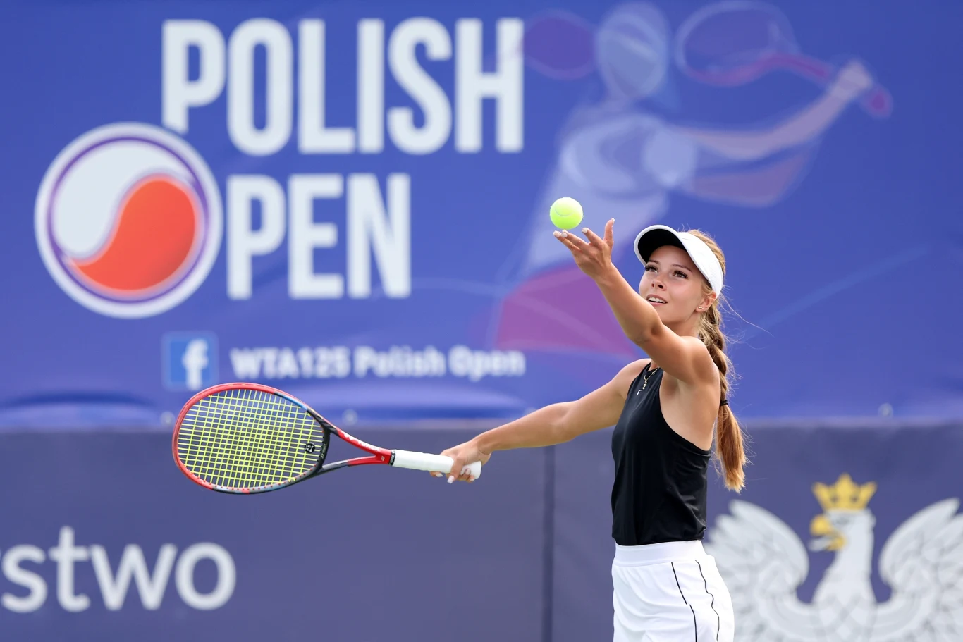 tenisistka w czarnej koszulce i białej czapce wykonuje serwis na korcie podczas turnieju Polish Open, w tle widoczne logo turnieju oraz stylizowana sylwetka tenisistki