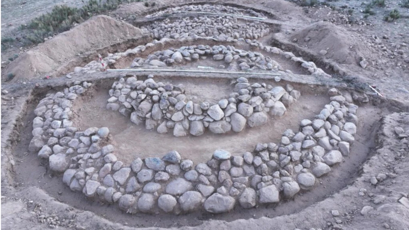 Odkryte kurhany kamienne kręgi ułożone koncentrycznie na wykopalisku archeologicznym z widocznymi warstwami ziemi i fragmentami odkrytych struktur