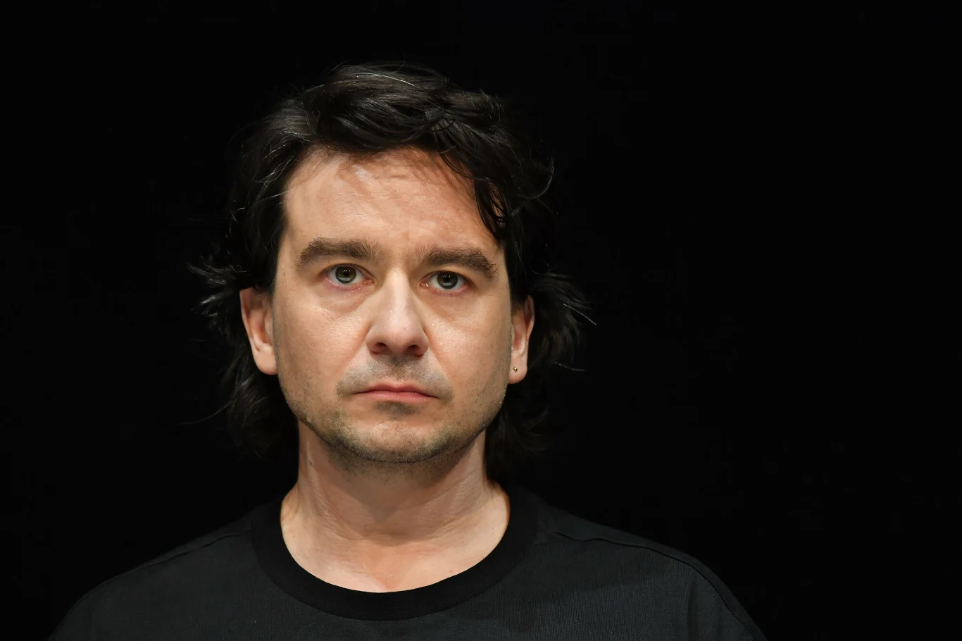 Maciej Bochniak w czasie 48. Festiwalu Polskich Filmów Fabularnych w Gdyni w 2023 roku Mężczyzna o ciemnych, lekko falowanych włosach i jasnej karnacji, ubrany w czarną koszulkę, patrzący poważnie na wprost na tle jednolitego czarnego tła.