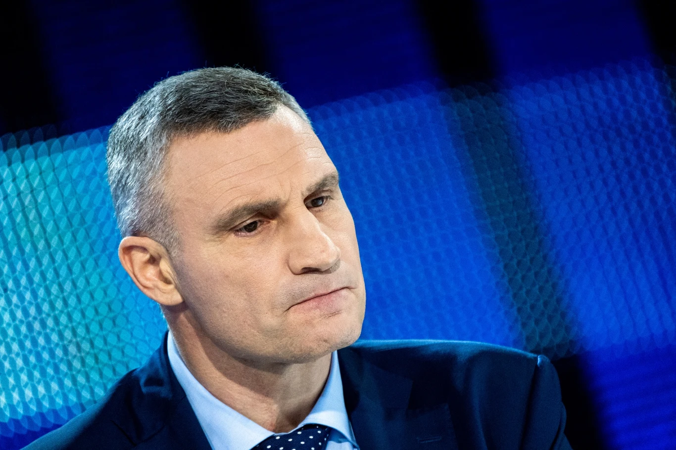 Witalij Kliczko Witalij Kliczko w garniturze i krawacie na tle niebieskiego, rozmytego tła.