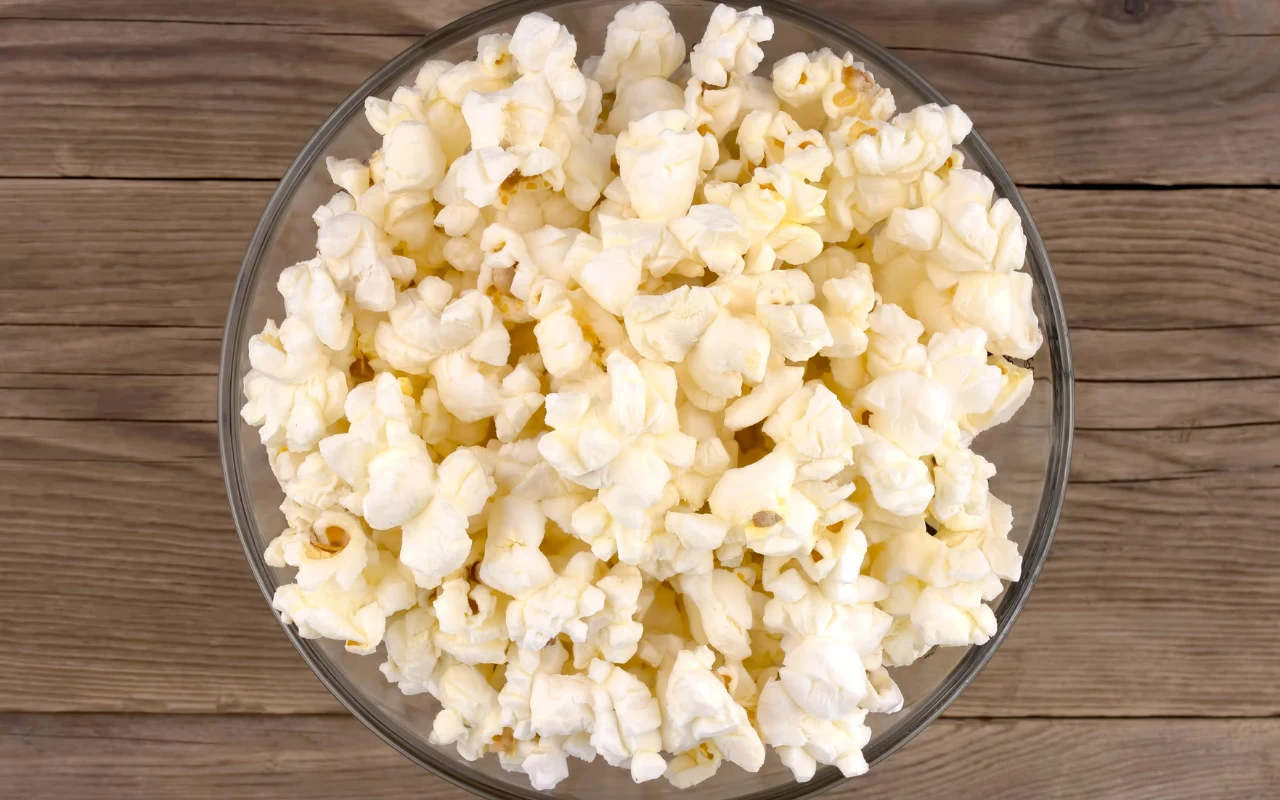 Miska pełna świeżo uprażonego popcornu ustawiona na drewnianym blacie.
