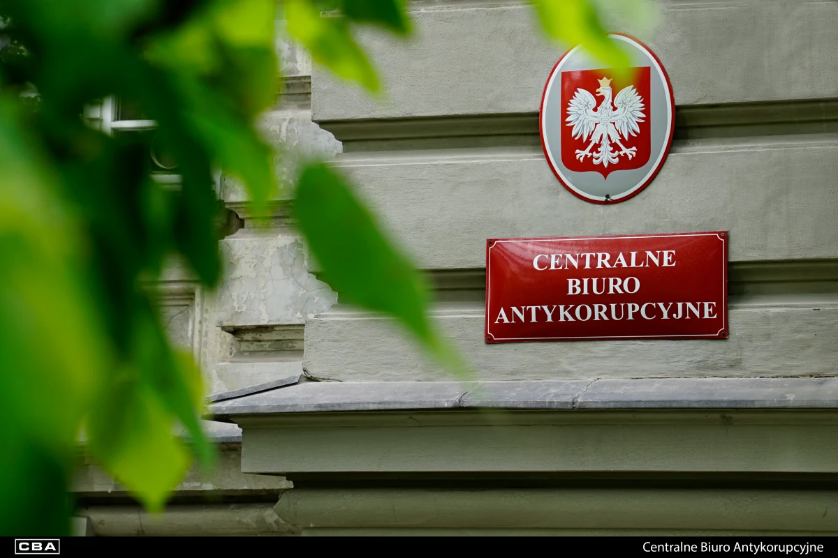 CBA prowadzi śledztwo w sprawie zmowy przetargowej Tablica z godłem Polski i napisem Centralne Biuro Antykorupcyjne na ścianie budynku, liście na pierwszym planie.