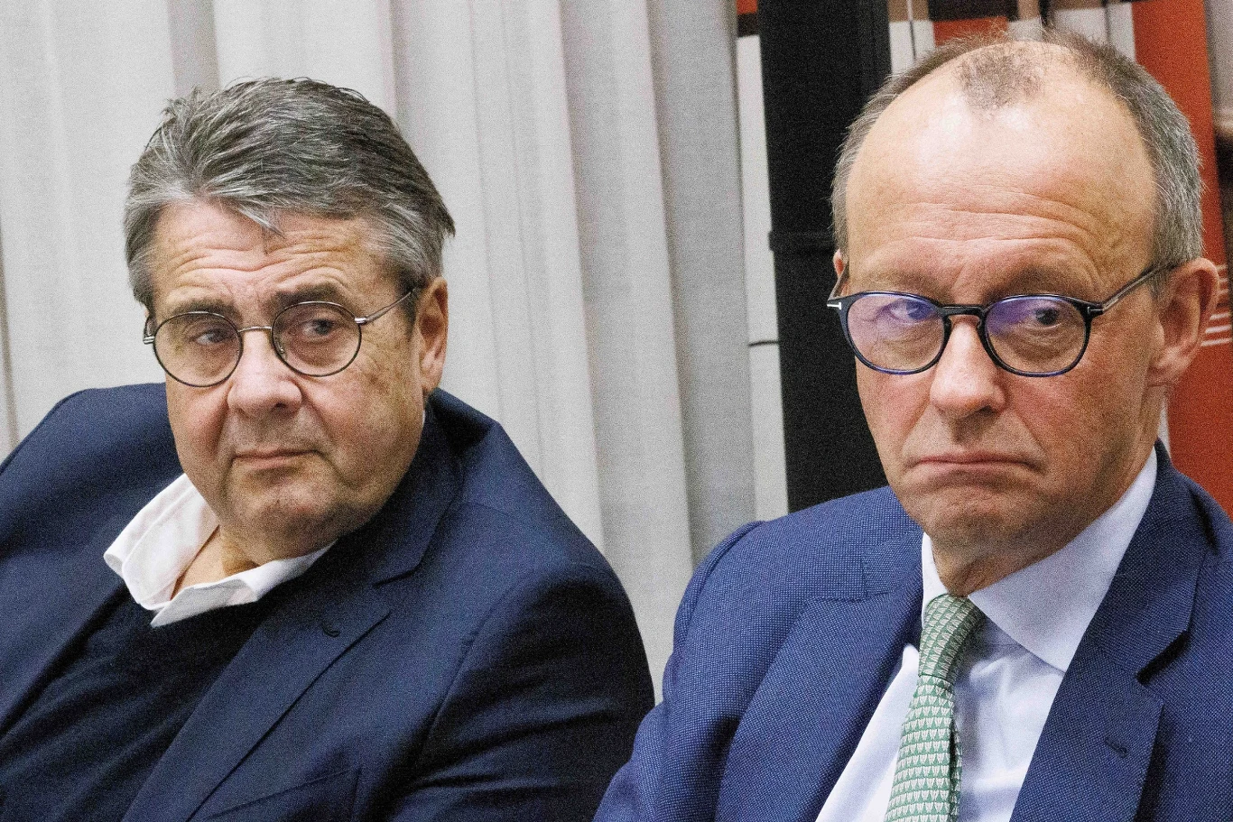 Daniel Goffart oraz kanclerz Niemiec Friedrich Merz Dwóch mężczyzn w średnim wieku w garniturach i okularach siedzi obok siebie, patrząc poważnie w tym samym kierunku.