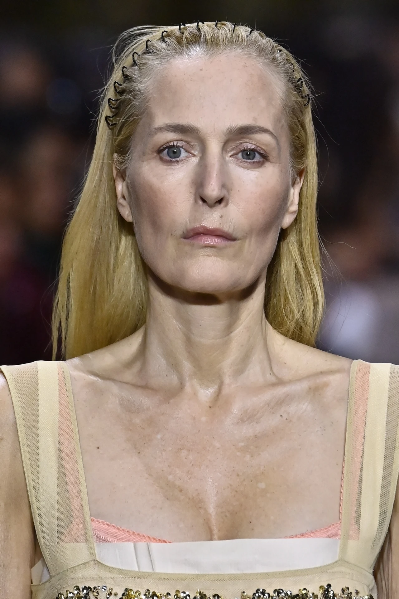 Aktorka jest jedną z gwiazd Hollywood, które zachwycają po 50. roku życia Kobieta o blond włosach spiętych opaską, w beżowo-kremowej sukience z różowym ramiączkiem i delikatnymi zdobieniami, patrząca poważnie przed siebie.
