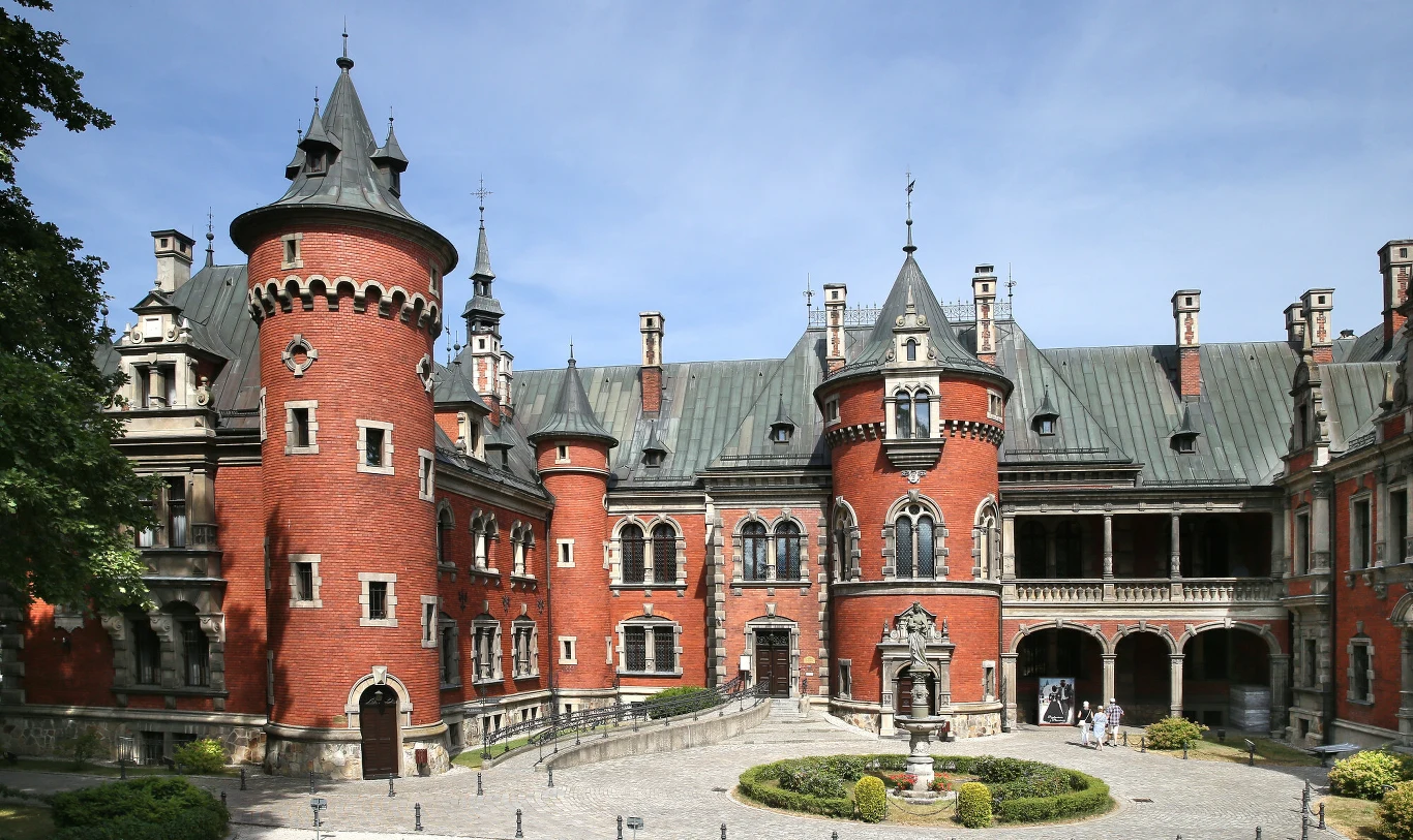 Odkryj Zespół Pałacowo-Parkowy w Pławniowicach Zespół pałacowo-parkowy w Pławniowicach z ceglanym zamkiem, wieżami, dziedzińcem i centralną fontanną.