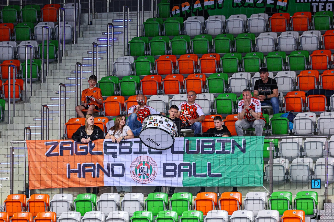 Fani piłki ręcznej z Lubina przeżyli w tym sezonie ogromne rozczarowanie Grupa kibiców Zagłębia Lubin z dużym bębnem i klubową flagą na trybunach hali sportowej wśród kolorowych siedzeń.