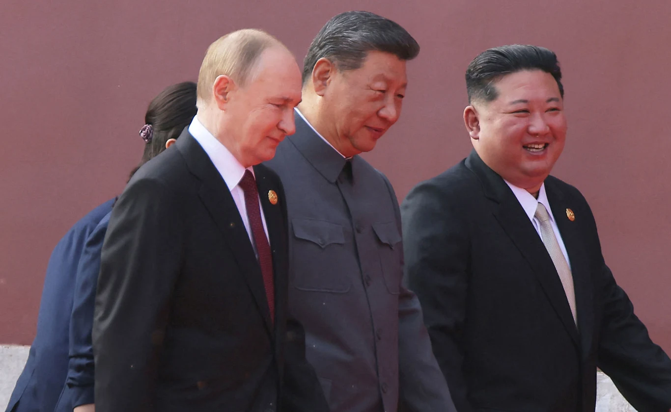 Wrzesień 2025. Władimir Putin, Xi Jinping i Kim Dzong Un w Pekinie Trzech mężczyzn ubranych w eleganckie garnitury i mundur idzie razem, uśmiechając się i rozmawiając.