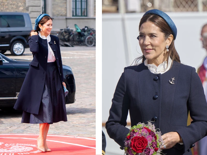 Królowa Maria podczas rozpoczęcia sezonu żeglarskiego Elegancka kobieta w granatowym płaszczu oraz opasce na głowie, trzymająca bukiet kwiatów i stojąca na zewnątrz w miejskiej scenerii.