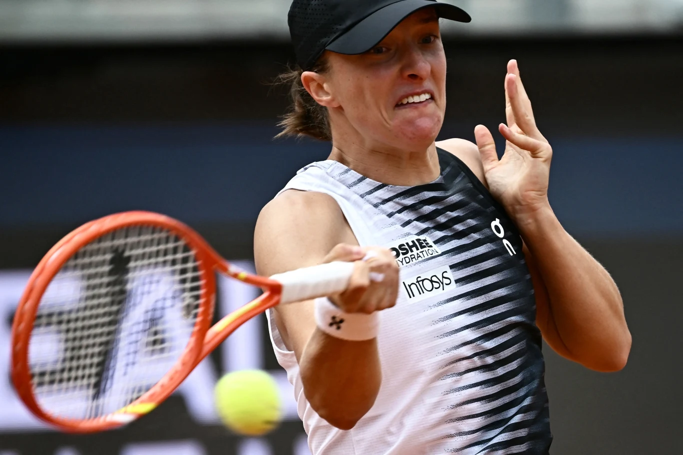 Zawodniczka w sportowej koszulce i czapce uderza piłkę tennisową rakietą, skupiając się na precyzyjnym zagraniu.
