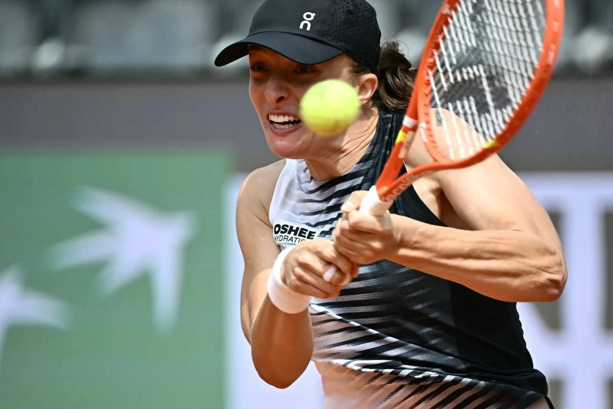 Zawodniczka w sportowej koszulce i czapce z daszkiem uderza piłkę tenisową rakietą, skupiona na grze.