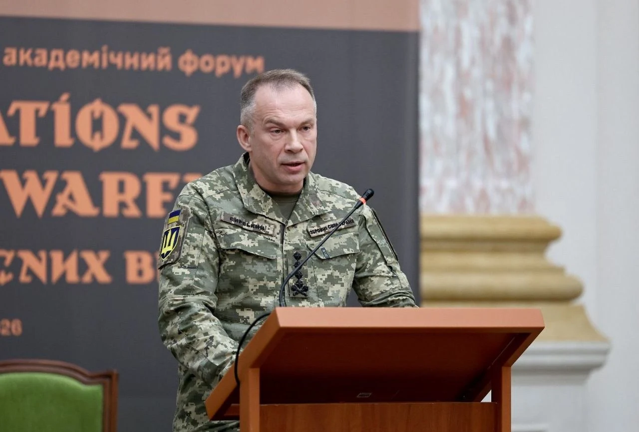 Rosja zwiększa produkcję dronów bojowych. Gen. Syrski ostrzega Mężczyzna w mundurze wojskowym przemawia przy mównicy, w tle baner i element architektoniczny.