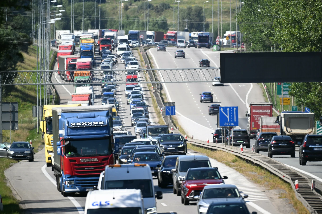 Korek drogowy na autostradzie z dużą liczbą samochodów osobowych i ciężarowych zajmujących wszystkie pasy ruchu w obu kierunkach.