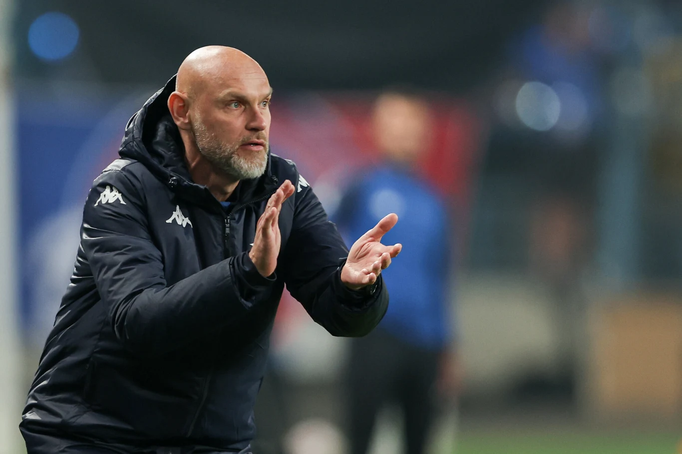 Mariusz Jop jako trener wprowadził Wisłę Kraków do Ekstraklasy Mariusz Jop, trener Wisły Kraków, klaszcze w dłonie w sportowej kurtce podczas meczu piłkarskiego.