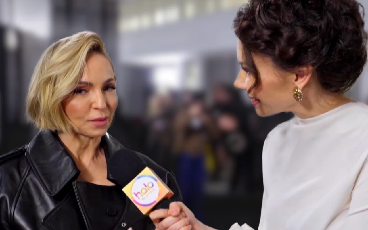 Kobieta w czarnej skórzanej kurtce udziela wywiadu reporterce trzymającej mikrofon z logo "halo", obie skupione na rozmowie.