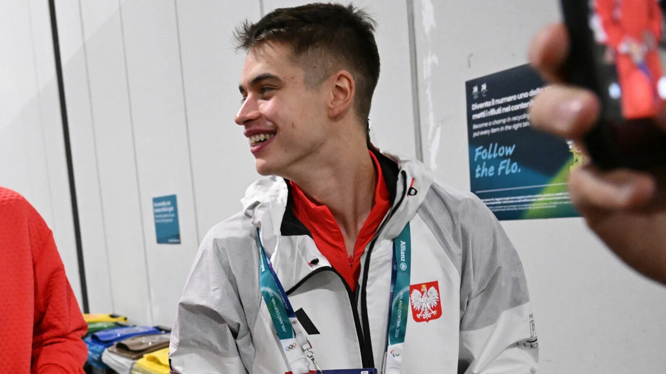 Władimir Semirunnij Uśmiechnięty młody mężczyzna w sportowej kurtce z polskim godłem oraz oficjalnym identyfikatorem na szyi, stojący w jasnym pomieszczeniu.