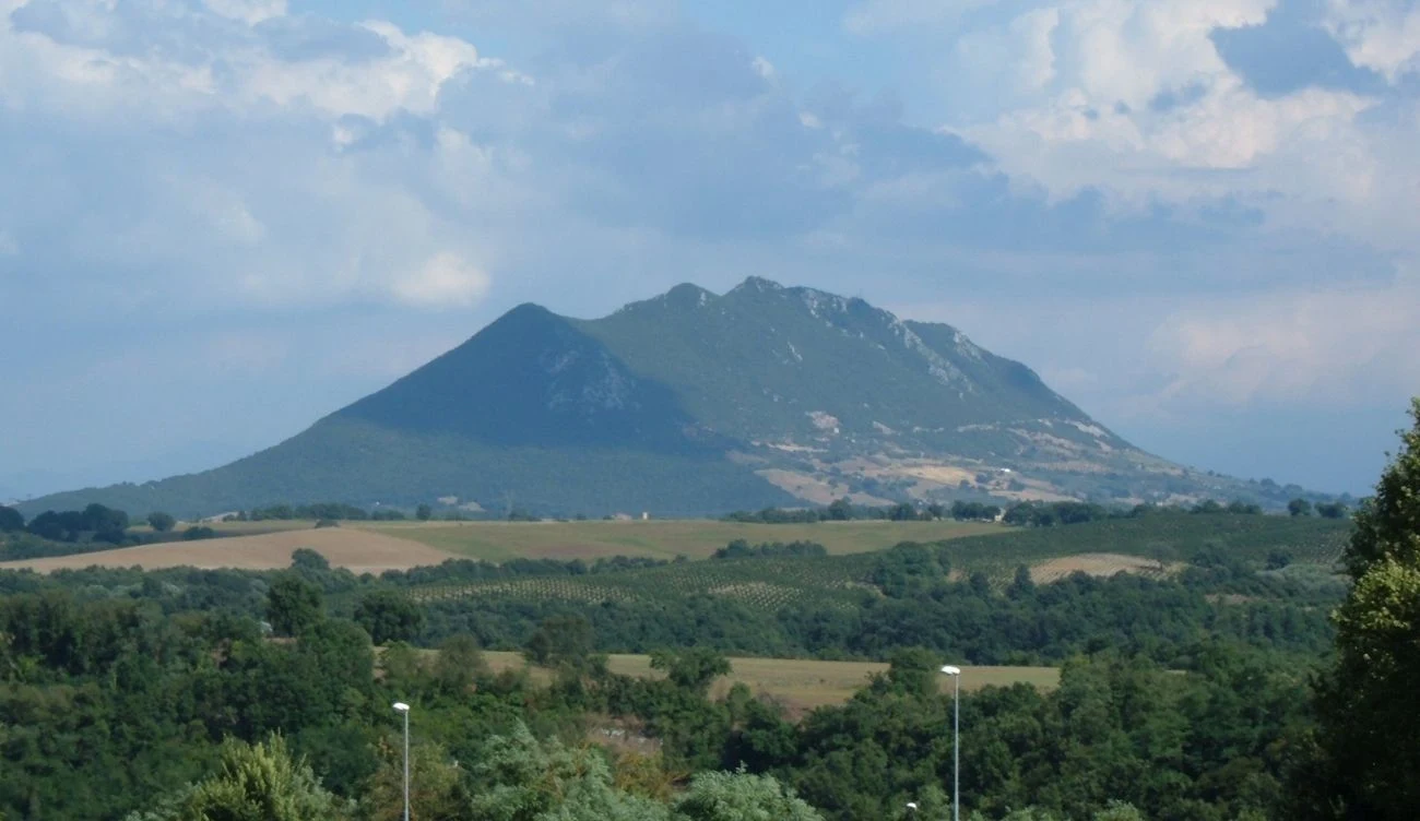 Monte Soratte to niezwykła góra na północ od Rzymu Monte Soratte w Lacjum, widziana od strony zielonych pól i lasów, pod niebem z chmurami, góruje nad okolicą.