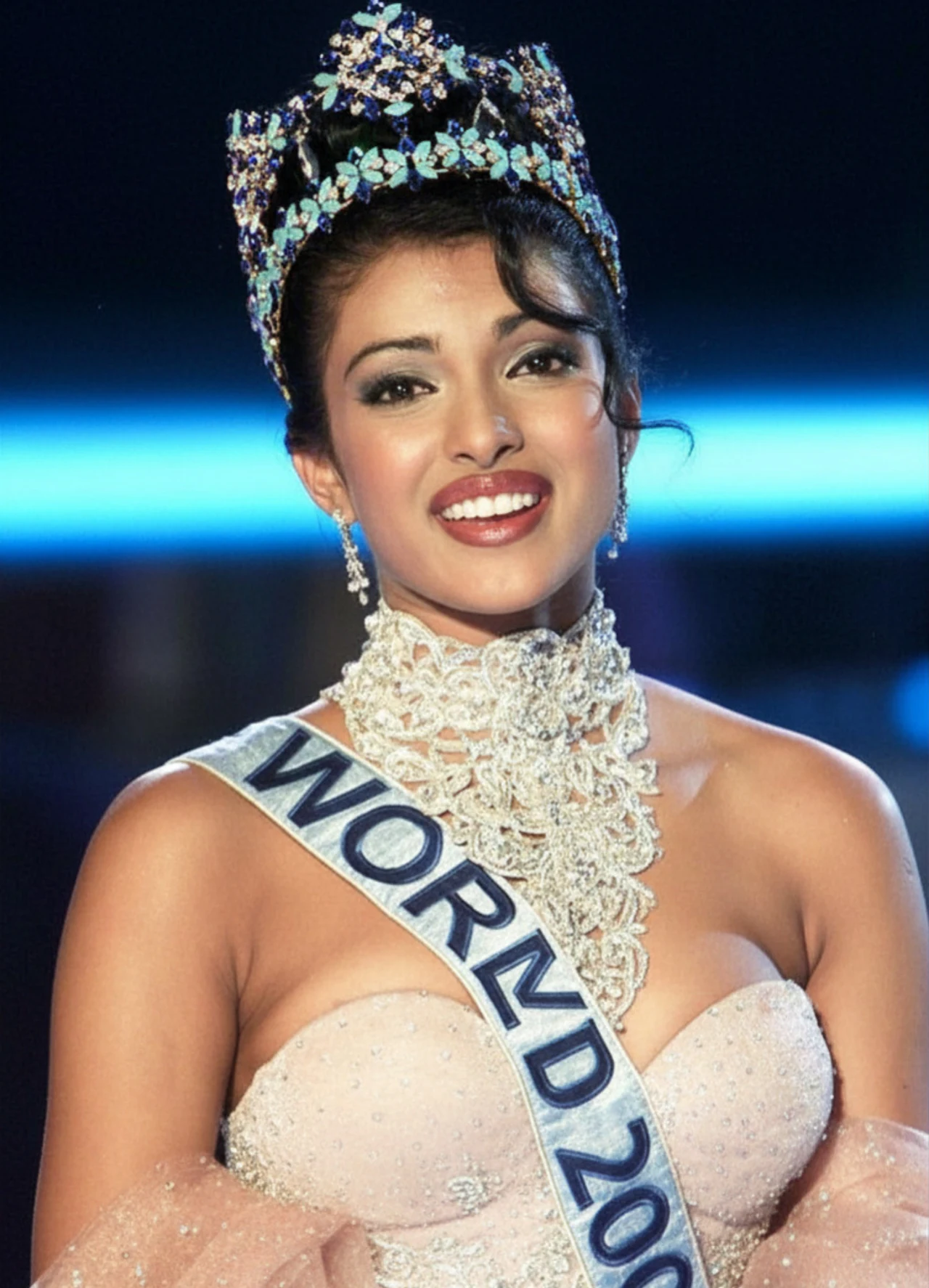Priyanka Chopra po wygraniu Miss World Młoda kobieta w bogato zdobionej koronie i z szarfą z napisem „WORLD 2000”, uśmiechnięta, ubrana w elegancką, jasnoróżową suknię z ozdobnym kołnierzem, stojąca na tle ciemnej sceny z niebieskim podświetleniem.