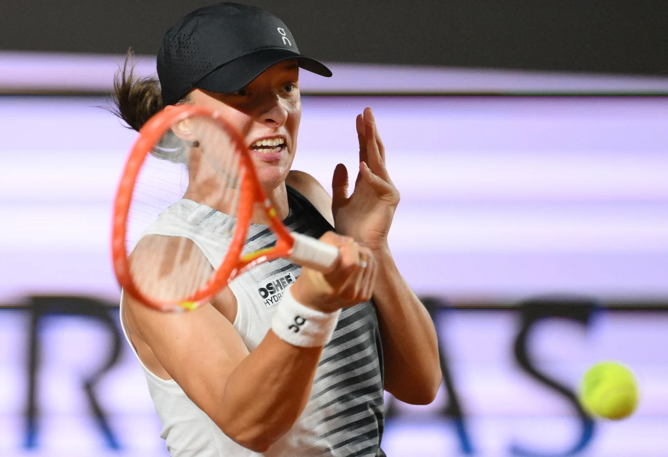 Tenisistka w sportowej czapce uderza piłkę forehandem podczas dynamicznego meczu.