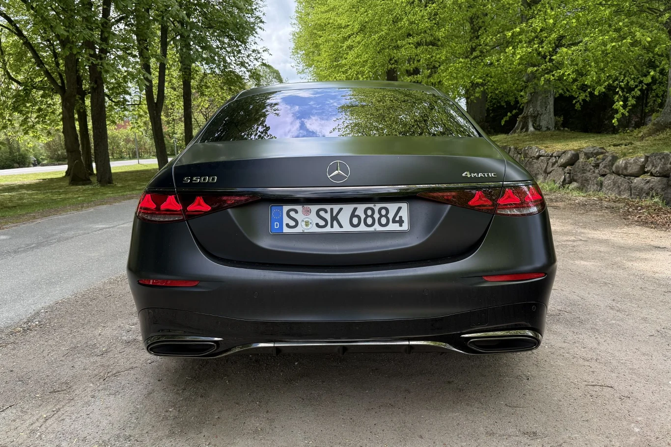Czarny Mercedes-Benz S 500 z napisem 4MATIC, widok od tyłu, charakterystyczne tylne światła LED oraz niemieckie tablice rejestracyjne, samochód ustawiony na leśnej drodze.