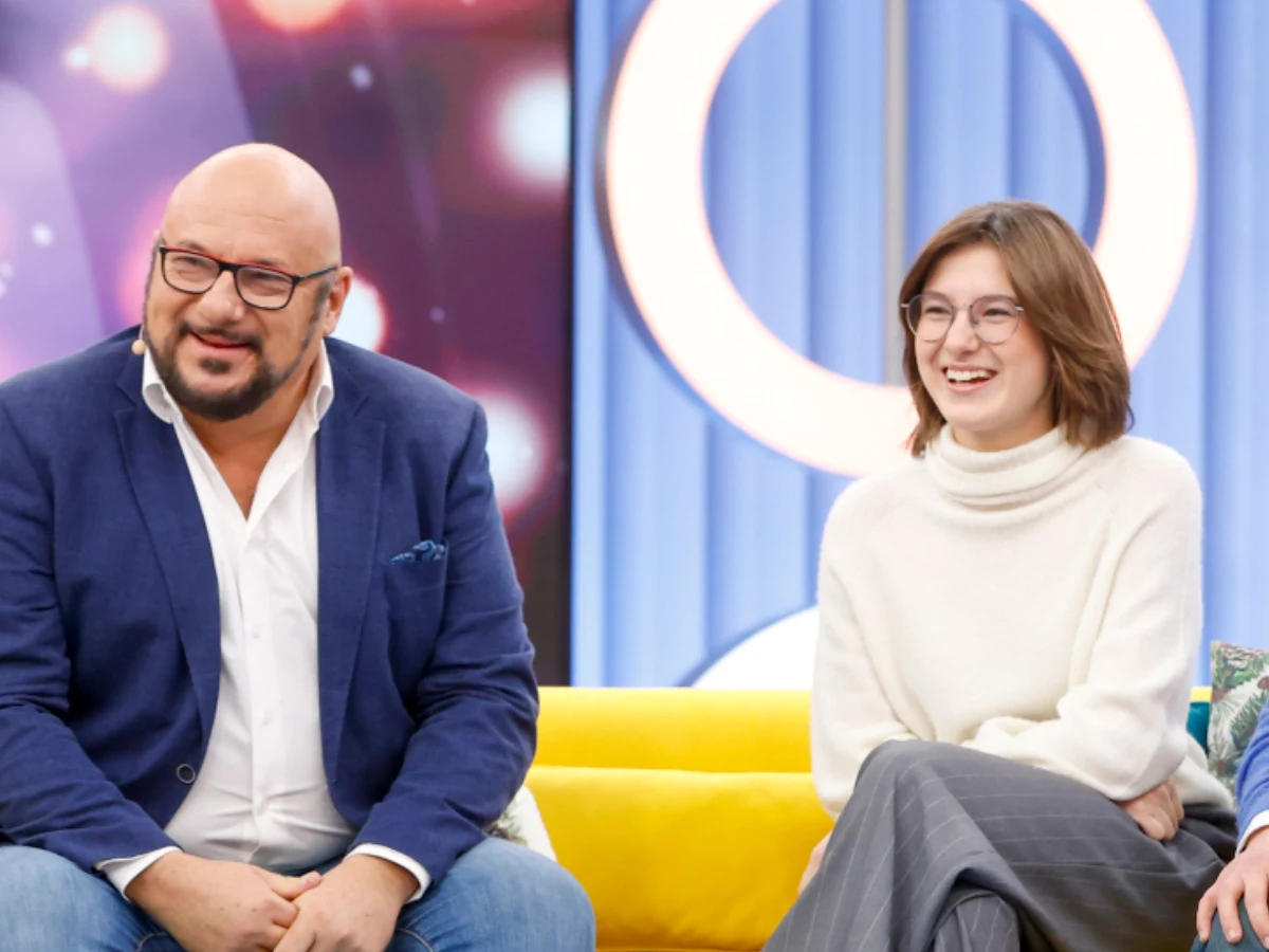 Piotr Gąsowski z córką, Julią Piotr Gąsowski z córką Julią na żółtej sofie. Mężczyzna w granatowej marynarce i kobieta w jasnej scenografii.