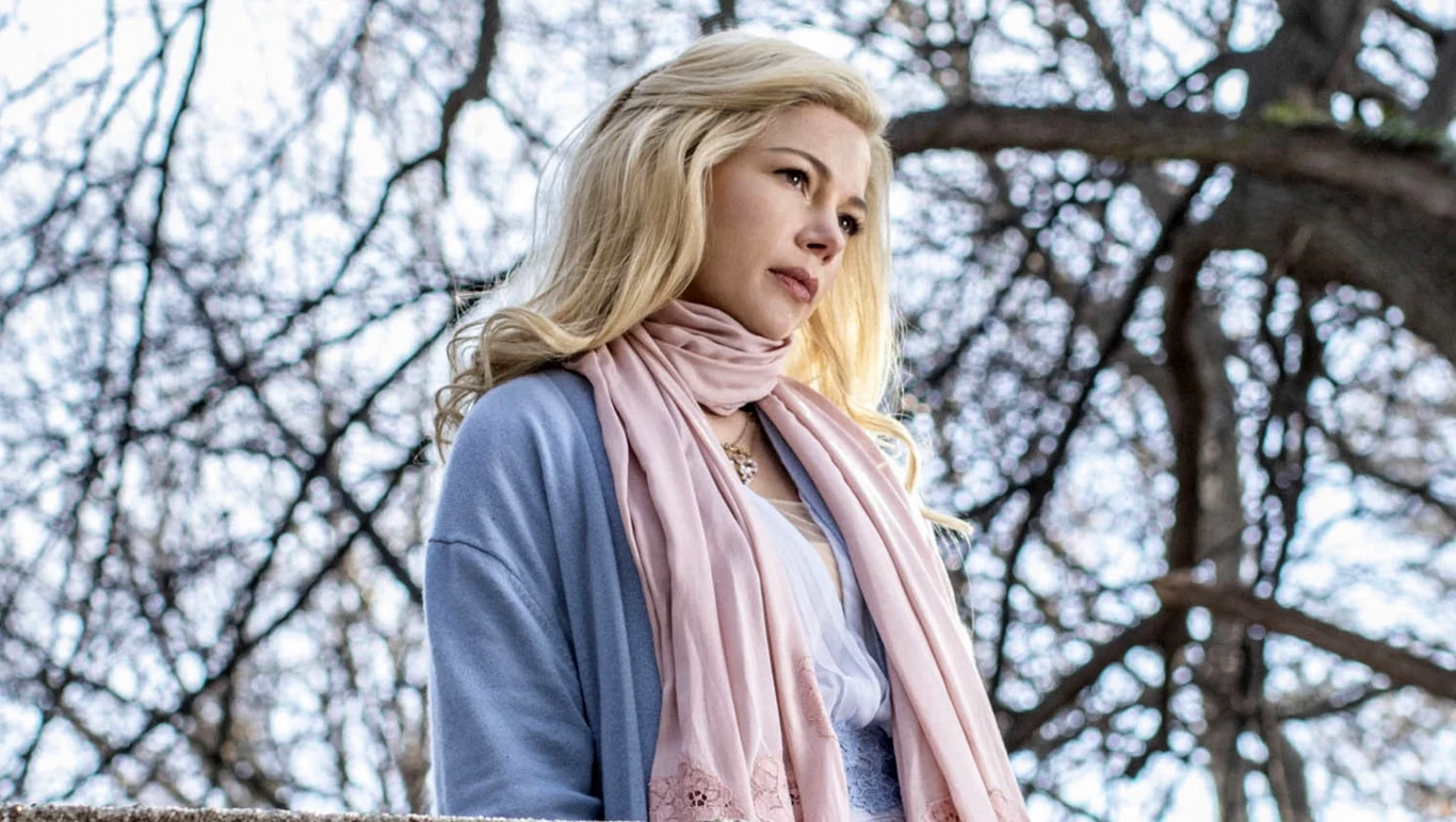 Michelle Williams w filmie "Król rozrywki" Michelle Williams jako postać z filmu "Król rozrywki" na tle rozgałęzionych, bezlistnych drzew.