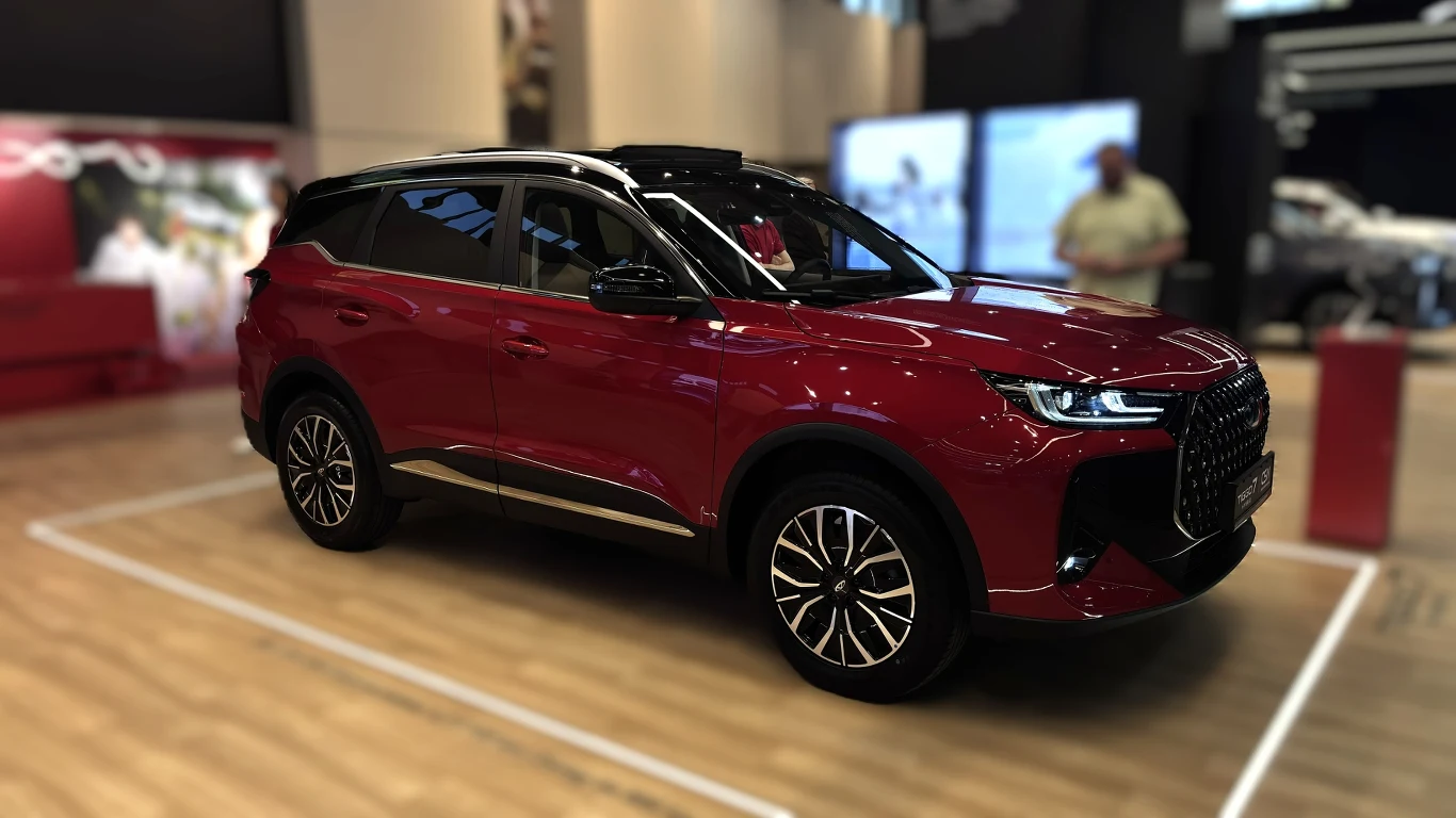 Nowością debiutującą podczas targów była hybrydowa wersja CHERY TIGGO 7 Czerwony SUV o dynamicznej sylwetce z dużym, czarnym grillem i atrakcyjnymi felgami prezentuje się w nowoczesnym, dobrze oświetlonym wnętrzu wystawowym.