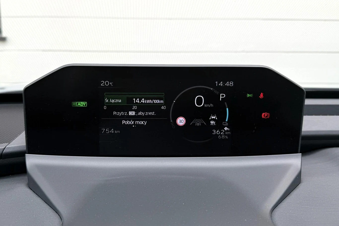 Cyfrowy panel wskaźników samochodu elektrycznego z widocznym poziomem naładowania akumulatora, prędkościomierzem ustawionym na 0 km/h oraz zasięgiem 362 km.