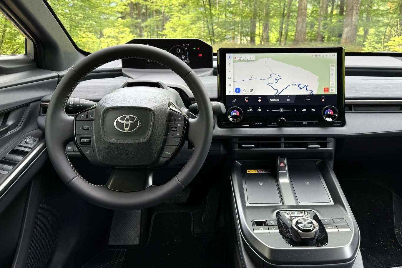 Nowoczesna deska rozdzielcza z cyfrowym wyświetlaczem, dużym ekranem nawigacji oraz wielofunkcyjną kierownicą z logo Toyoty.