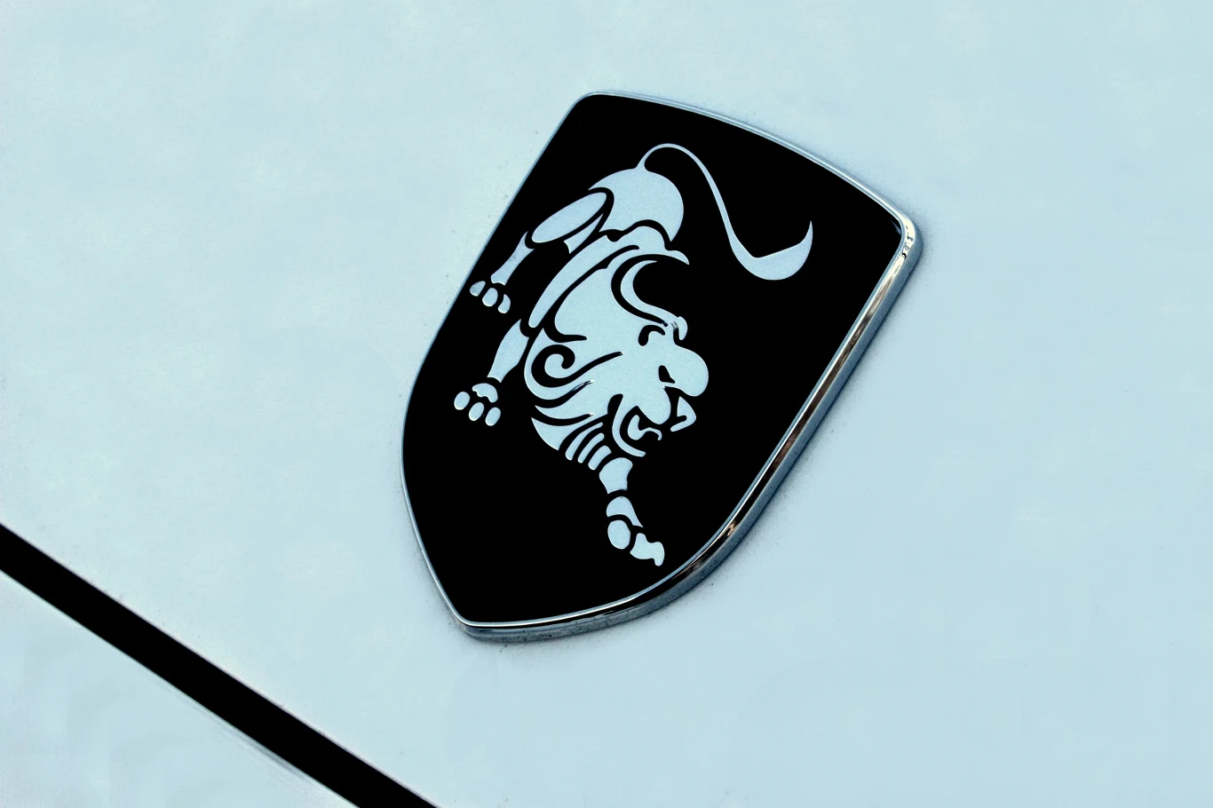 Czarny emblemat w kształcie tarczy z białym wizerunkiem stylizowanego byka umieszczony na jasnej powierzchni.