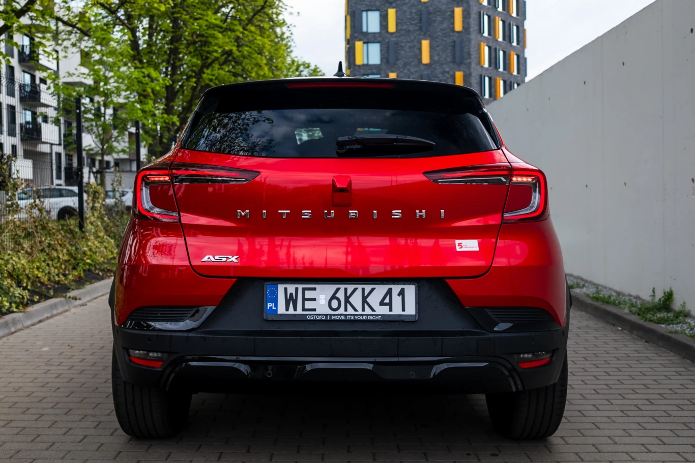 Wygląd tyłu w Mitsubishi ASX jest bardziej japoński niż francuski. Mimo że zmieniło się niewiele. Czerwony SUV Mitsubishi ASX zaparkowany tyłem na miejskiej ulicy, z wyraźnie widocznym logo marki i tablicą rejestracyjną.