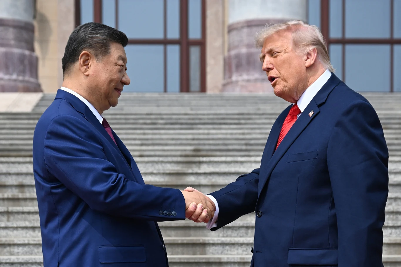 Donald Trump podczas spotkania z Xi Jinpingiem w Pekinie Donald Trump i Xi Jinping podają sobie ręce na tle szerokich schodów w Pekinie, obaj w garniturach.