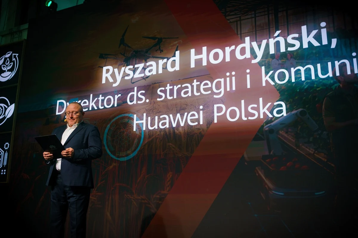 Mężczyzna w garniturze trzyma tablet i stoi na tle dużego ekranu z napisem 'Ryszard Hordyński, Dyrektor ds. strategii i komunikacji Huawei Polska' oraz grafiką przedstawiającą drona i rośliny.