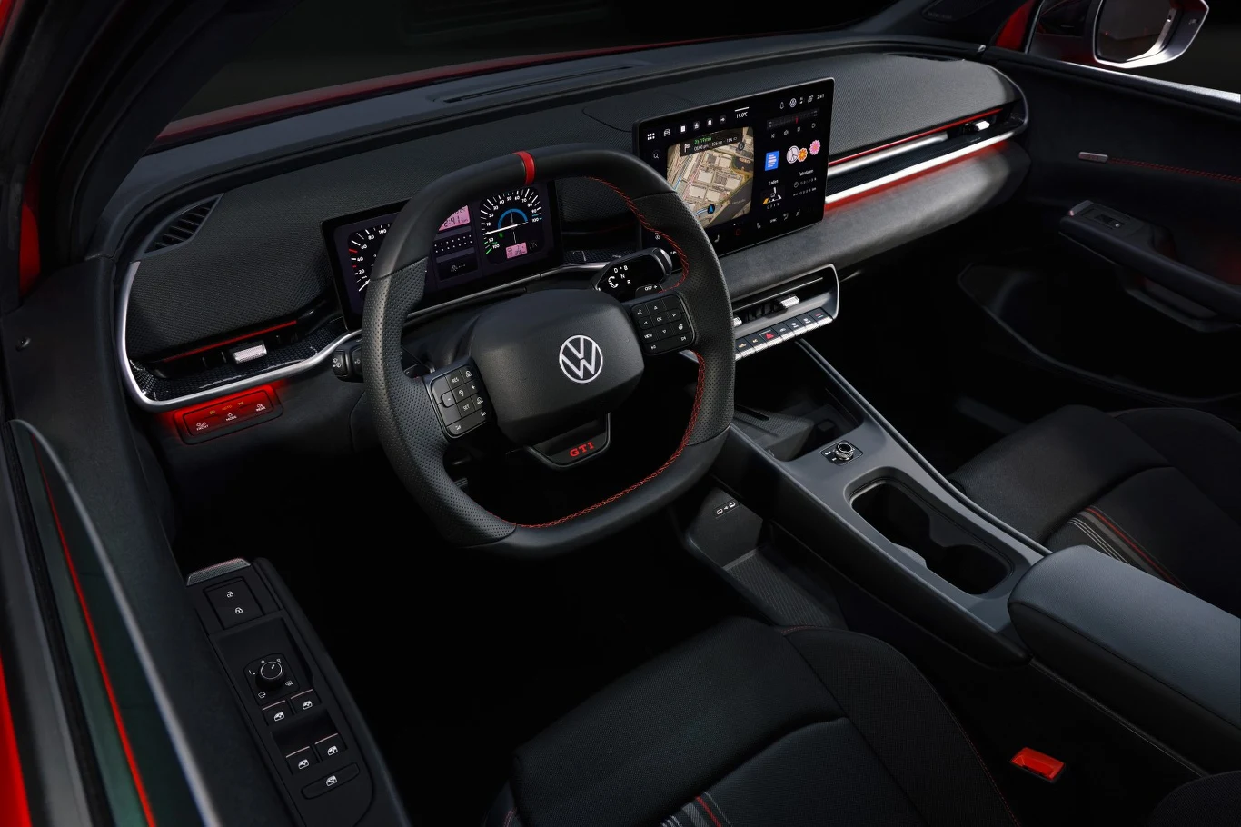 Kokpit samochodu Volkswagen z nowoczesną, cyfrową deską rozdzielczą, dużym ekranem multimedialnym, trójramienną kierownicą ze znakiem VW oraz podświetleniem ambientowym biegnącym przez całą szerokość deski.