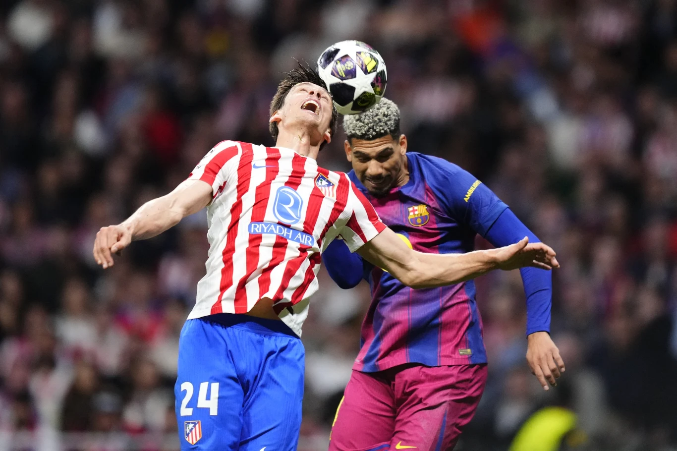 Kadr z meczu Atletico - Barcelona w rewanżowym ćwierćfinale Ligi Mistrzów Dwóch piłkarzy w trakcie walki o piłkę głowami, jeden w biało-czerwonej koszulce z numerem 24, drugi w bordowo-granatowym stroju; intensywna rywalizacja podczas meczu na stadionie.