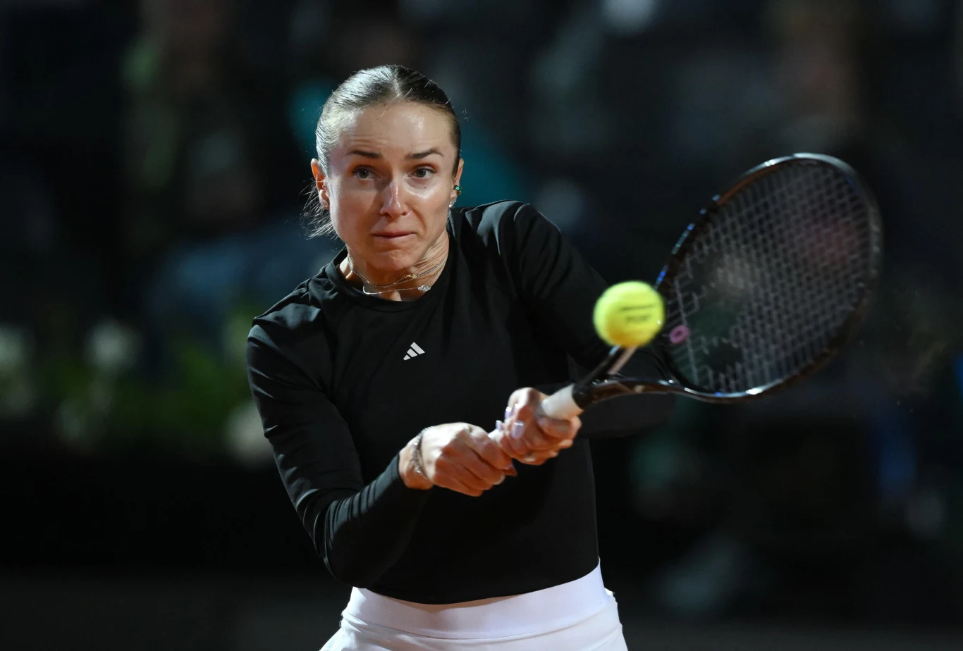 Kobieta w sportowym stroju skupiona podczas uderzenia piłki tenisowej rakietą.
