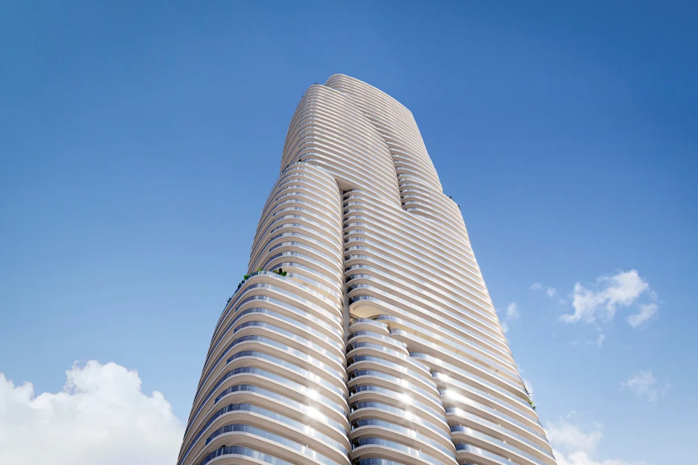 Nowoczesny, wielopiętrowy wieżowiec o zaokrąglonych kształtach i jasnej elewacji, wyróżniający się futurystyczną architekturą na tle błękitnego nieba.